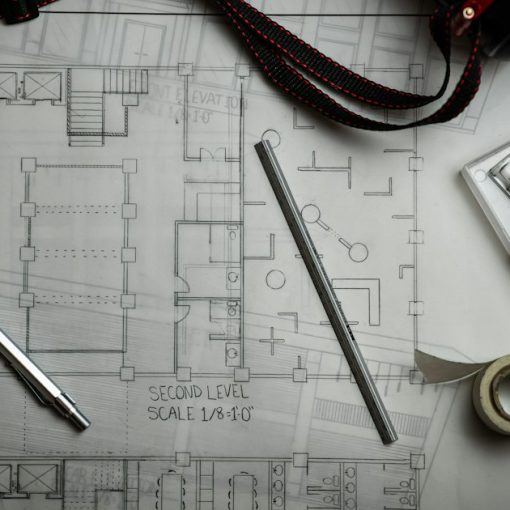 Architectural blueprints with drafting pencils and a metal ruler, illustrating Autodesk connecting desktop, mobile and cloud