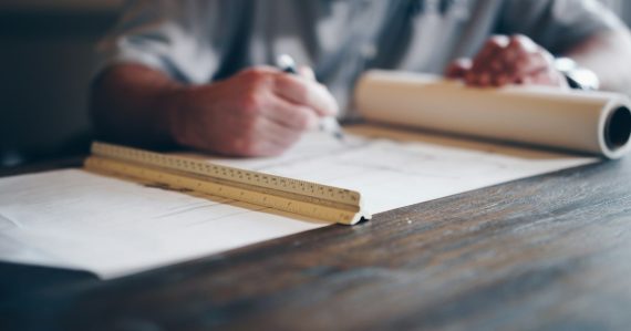 Person drafting on blueprint, illustrating Autodesk moving software to the cloud
