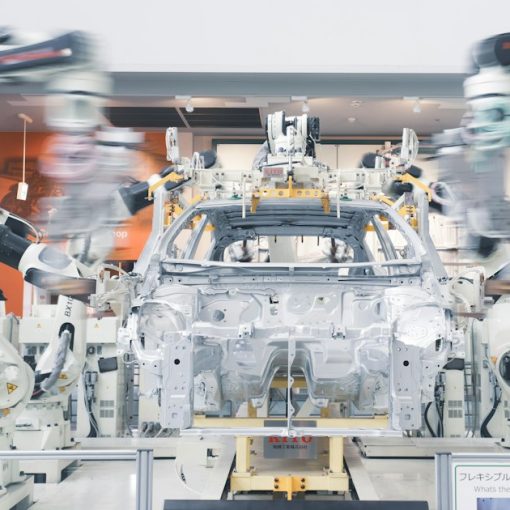 Robotic arms assembling a car chassis on a factory line, illustrating cloud computing in the automotive industry
