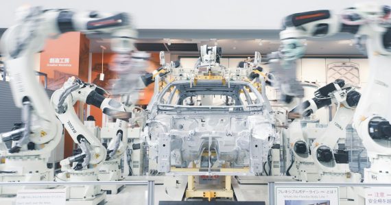 Robotic arms assembling a car chassis on a factory line, illustrating cloud computing in the automotive industry