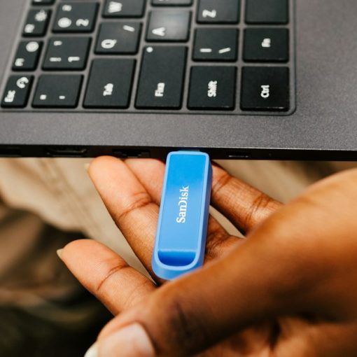 A hand inserting a USB drive into a laptop, illustrating managing backups in virtual environments