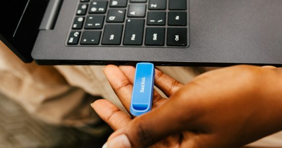 A hand inserting a USB drive into a laptop, illustrating managing backups in virtual environments