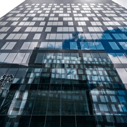 A tall building reflects the sky's clouds, illustrating banks moving to the cloud