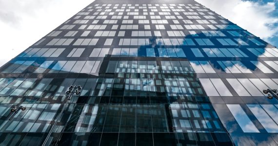 A tall building reflects the sky's clouds, illustrating banks moving to the cloud
