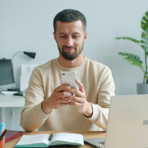 Man smiling while looking at his smartphone, illustrating bring your own device