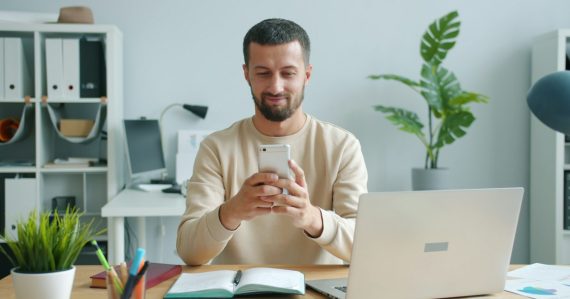 Man smiling while looking at his smartphone, illustrating bring your own device