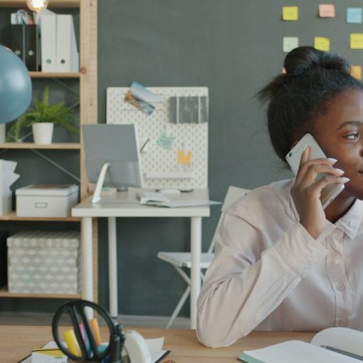 Woman talking on phone at desk in office, illustrating broadband and VoIP basics