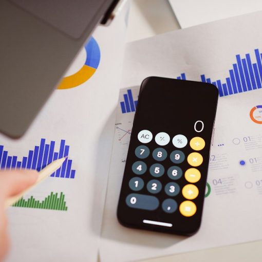 A calculator sitting on top of a table next to a laptop, illustrating cloud bringing IT budgets under control