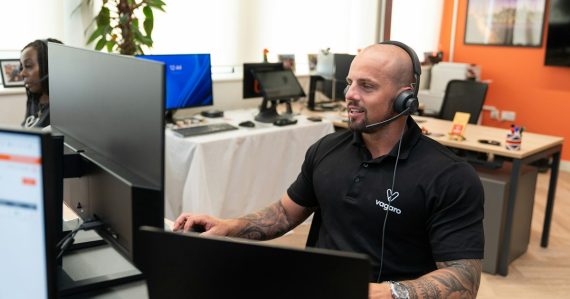 A man wearing a headset in front of a computer, illustrating cloud and big data benefits for BPO