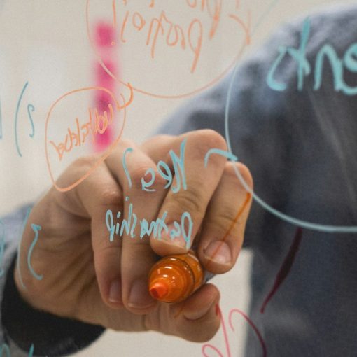 Person writing on glass whiteboard with diagrams, illustrating including the cloud in business strategy