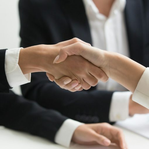 Two people shaking hands in front of a laptop, illustrating cloud computing and business success
