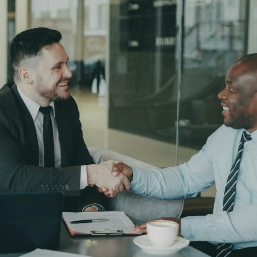Two businessmen shaking hands across a table, illustrating business virtualization benefits