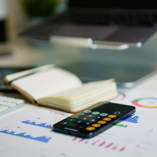 Office desk with smartphone and financial charts, illustrating CFOs getting involved with IT through the cloud