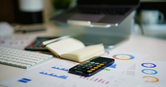 Office desk with smartphone and financial charts, illustrating CFOs getting involved with IT through the cloud