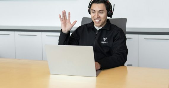 A man wearing headphones sitting in front of a laptop computer, illustrating call centers cutting costs with the cloud