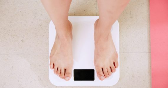 Person standing on white digital bathroom scale, illustrating the cloud is not a quick fix