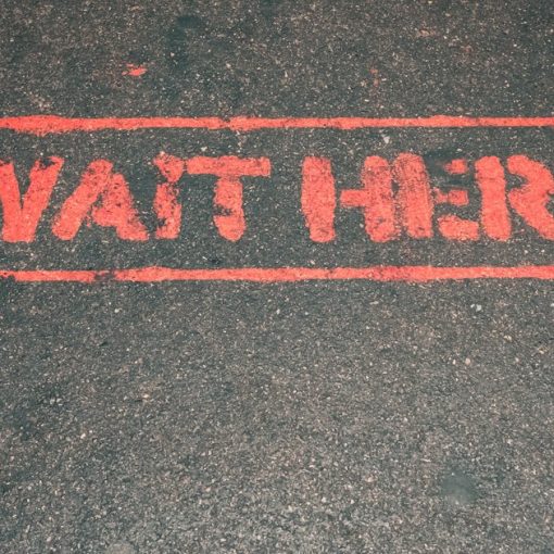 A red street sign that reads wait here, illustrating CFOs delaying cloud adoption