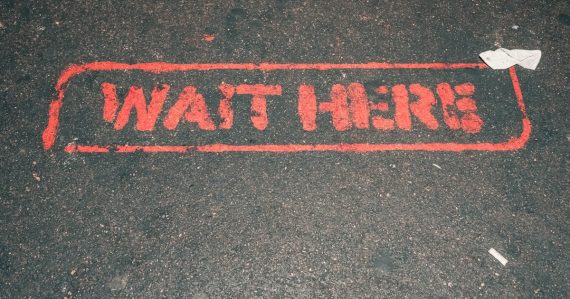 A red street sign that reads wait here, illustrating CFOs delaying cloud adoption