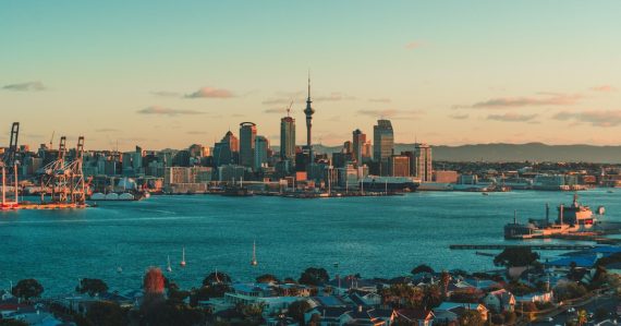 The Auckland skyline and harbor under a warm low sun in New Zealand, illustrating cloud adoption after the Christchurch quake