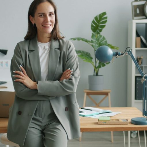 A woman executive in a grey suit smiles with arms crossed, illustrating CIO career prospects in the cloud era