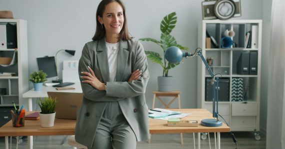 A woman executive in a grey suit smiles with arms crossed, illustrating CIO career prospects in the cloud era