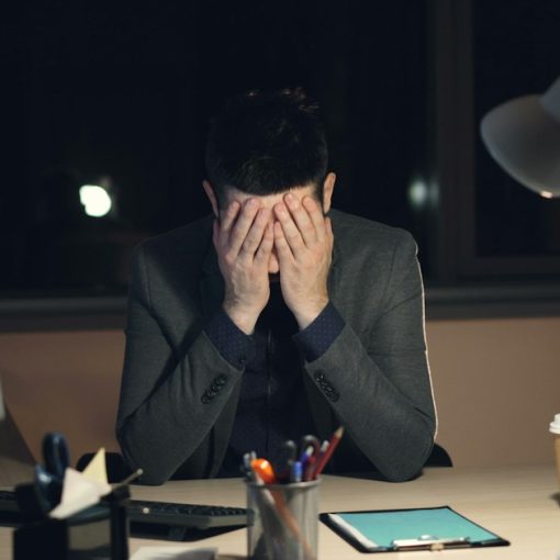 Man in suit sits at desk with head in hands, illustrating CIOs worried by cloud computing