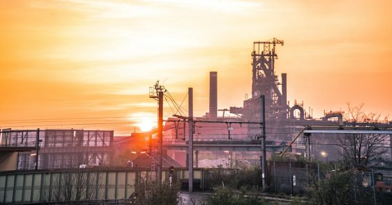 Industrial complex silhouetted against a bright sunset, illustrating client virtualization in the cloud