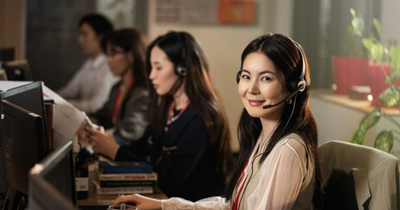 Smiling call center agent wearing a headset at a computer, illustrating a cloud call center