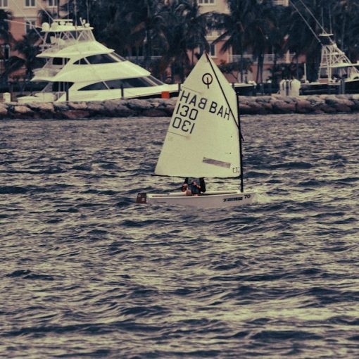 Small sailboat on choppy water with buildings behind, illustrating cloud lowering the bar for competitors