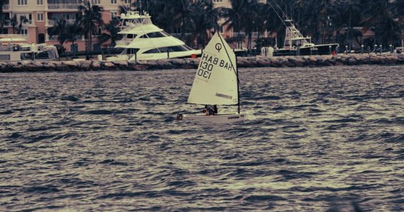 Small sailboat on choppy water with buildings behind, illustrating cloud lowering the bar for competitors