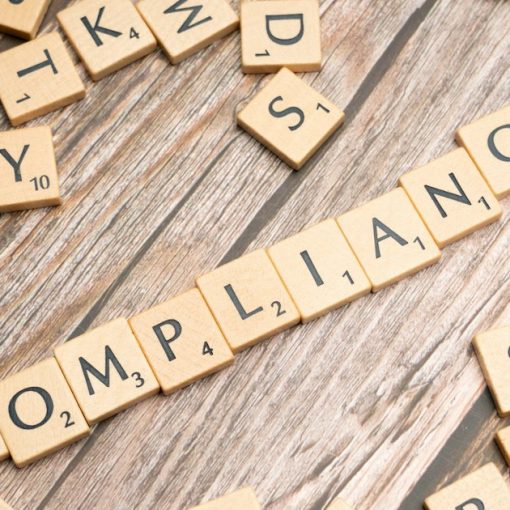 The word compliance spelled in wooden letter tiles, illustrating cloud compliance challenges