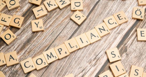 The word compliance spelled in wooden letter tiles, illustrating cloud compliance challenges