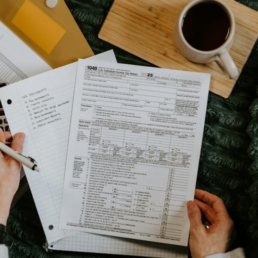 Person reviewing documents with calculator and laptop, illustrating cloud computing for accountants