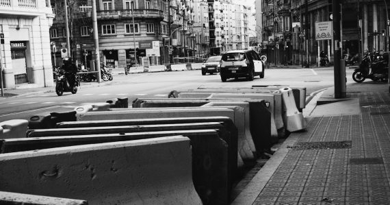 Concrete barriers line a city street with traffic, illustrating obstacles to cloud computing adoption
