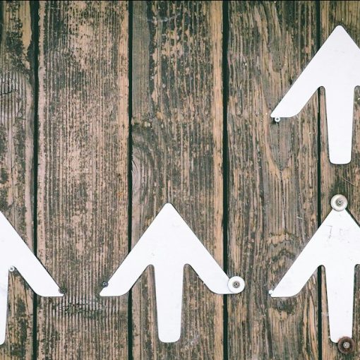 Several white arrows pointing upwards on a wooden wall, illustrating how cloud computing will change IT