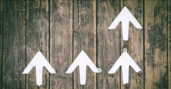 Several white arrows pointing upwards on a wooden wall, illustrating how cloud computing will change IT