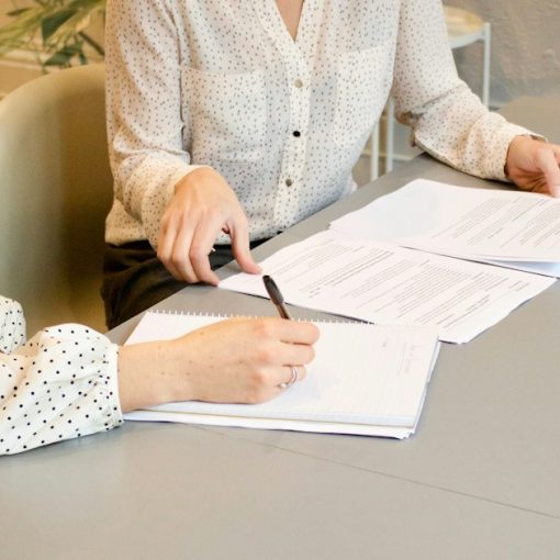 Woman signing documents beside a colleague, illustrating cloud computing contracts and services