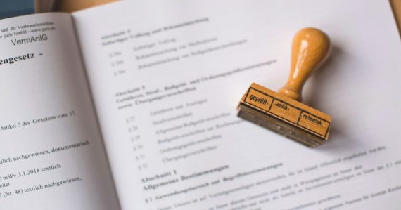 A wooden rubber stamp resting on an open legal document, illustrating legal issues in cloud computing