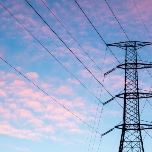 Black electric pylon under orange clouds, illustrating cloud computing compared to a power grid