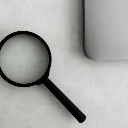 Magnifying glass sits near a laptop on a table, illustrating myths of cloud computing