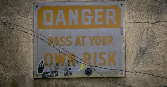 A sign on a wall that says danger pass at your own risk, illustrating the top risks of cloud computing