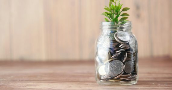 A glass jar filled with coins and a plant, illustrating cloud computing saving firms money