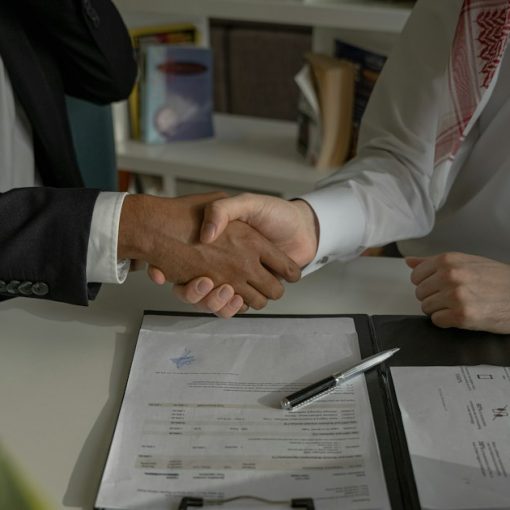 Two people shaking hands over a piece of paper, illustrating new skills for cloud security professionals