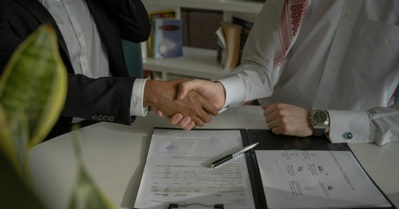 Two people shaking hands over a piece of paper, illustrating new skills for cloud security professionals