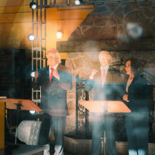 Three people stand behind podiums on a stage, illustrating the debate over cloud standards