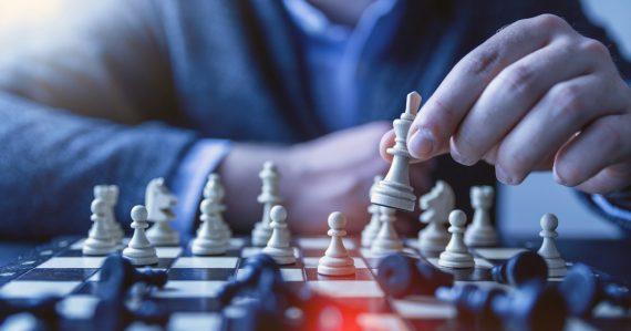 Man moving a chess piece on a chessboard, illustrating cloud computing strategies