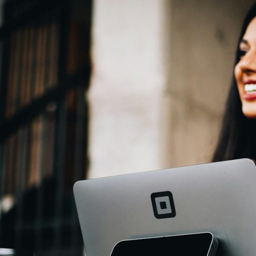 A woman smiling at a customer holding a coffee cup at a checkout, illustrating cloud economics and the customer experience