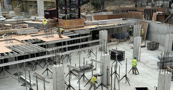 A group of men standing around a building under construction, illustrating companies ill-prepared for cloud goals