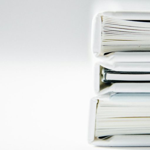 A stack of thick folders on a white surface, illustrating cloud governance beyond security