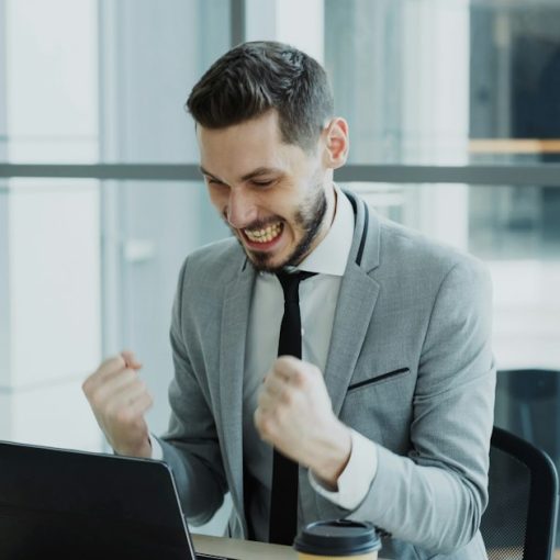 Businessman celebrating success at his laptop, illustrating cloud computing living up to the hype
